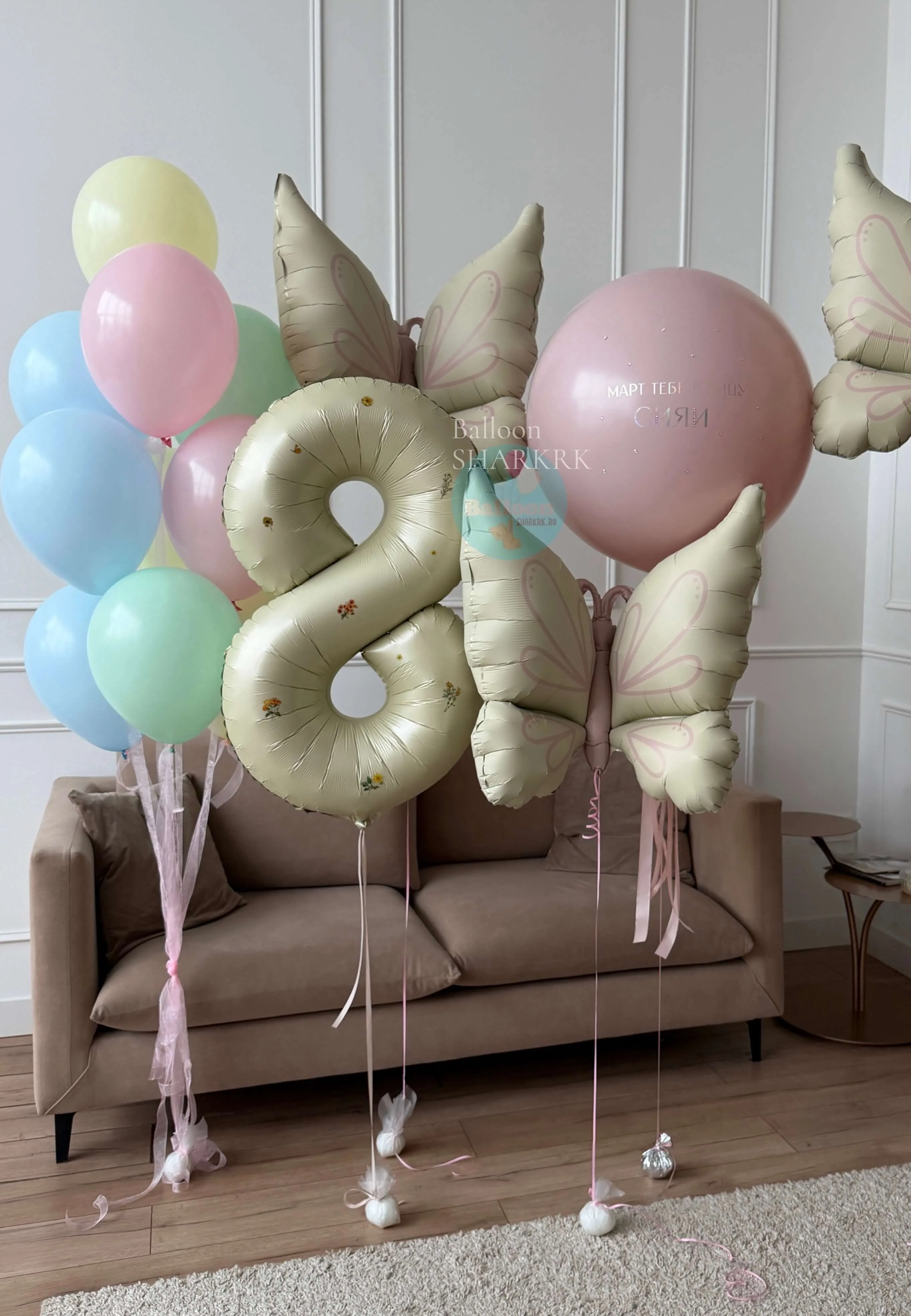 Оформление из воздушных шаров: цифра „8“ из кремовой фольги, фольгированные бабочки, шары мягких пастельных тонов. Ленты и декоративные элементы дополняют композицию.