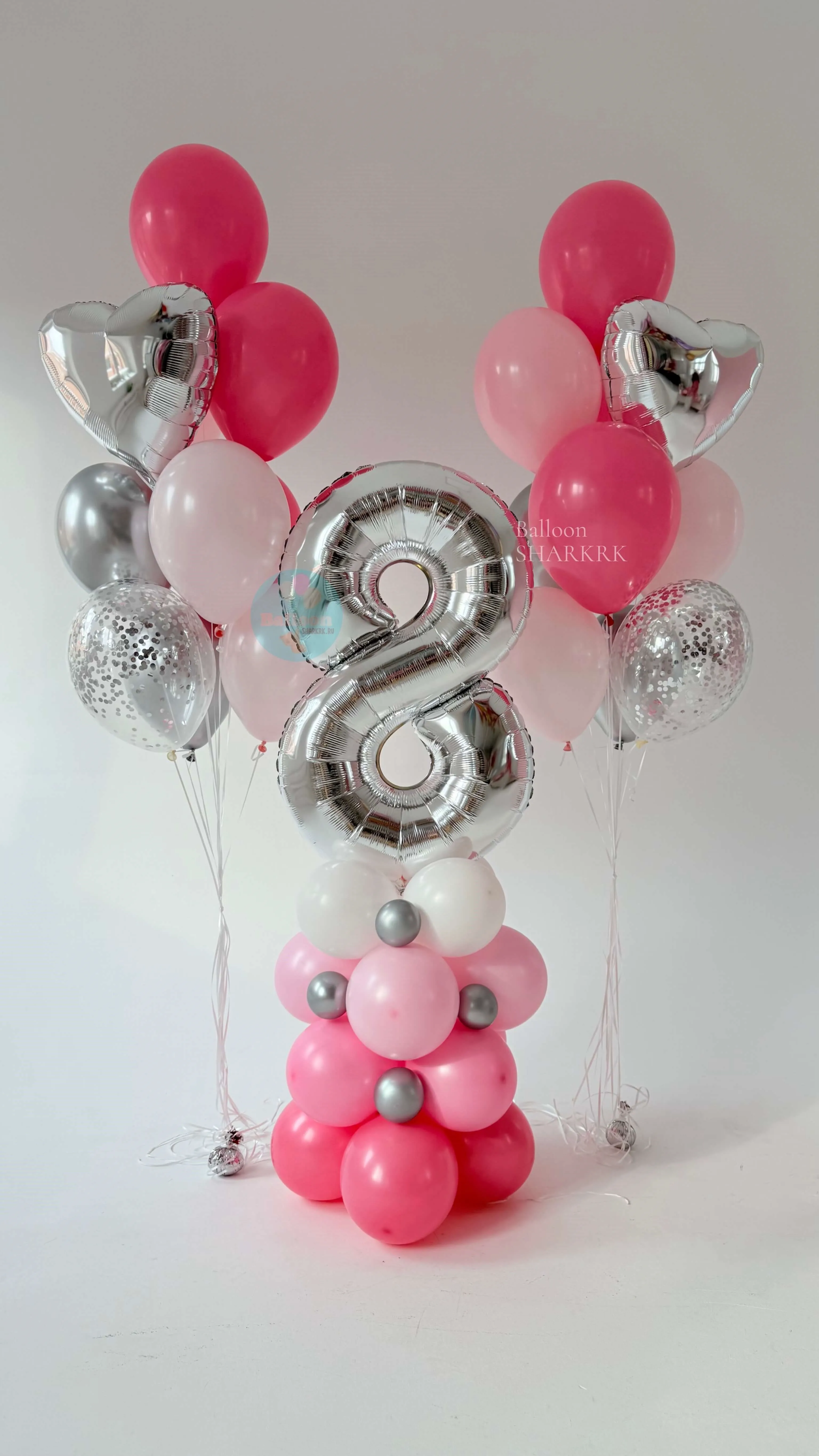 Декоративная композиция к 8 Марта: цифра „8“ из серебристой фольги, розовые и белые шары, серебристые элементы (сердечки, шары с конфетти), основание из шаров формирует устойчивую конструкцию
