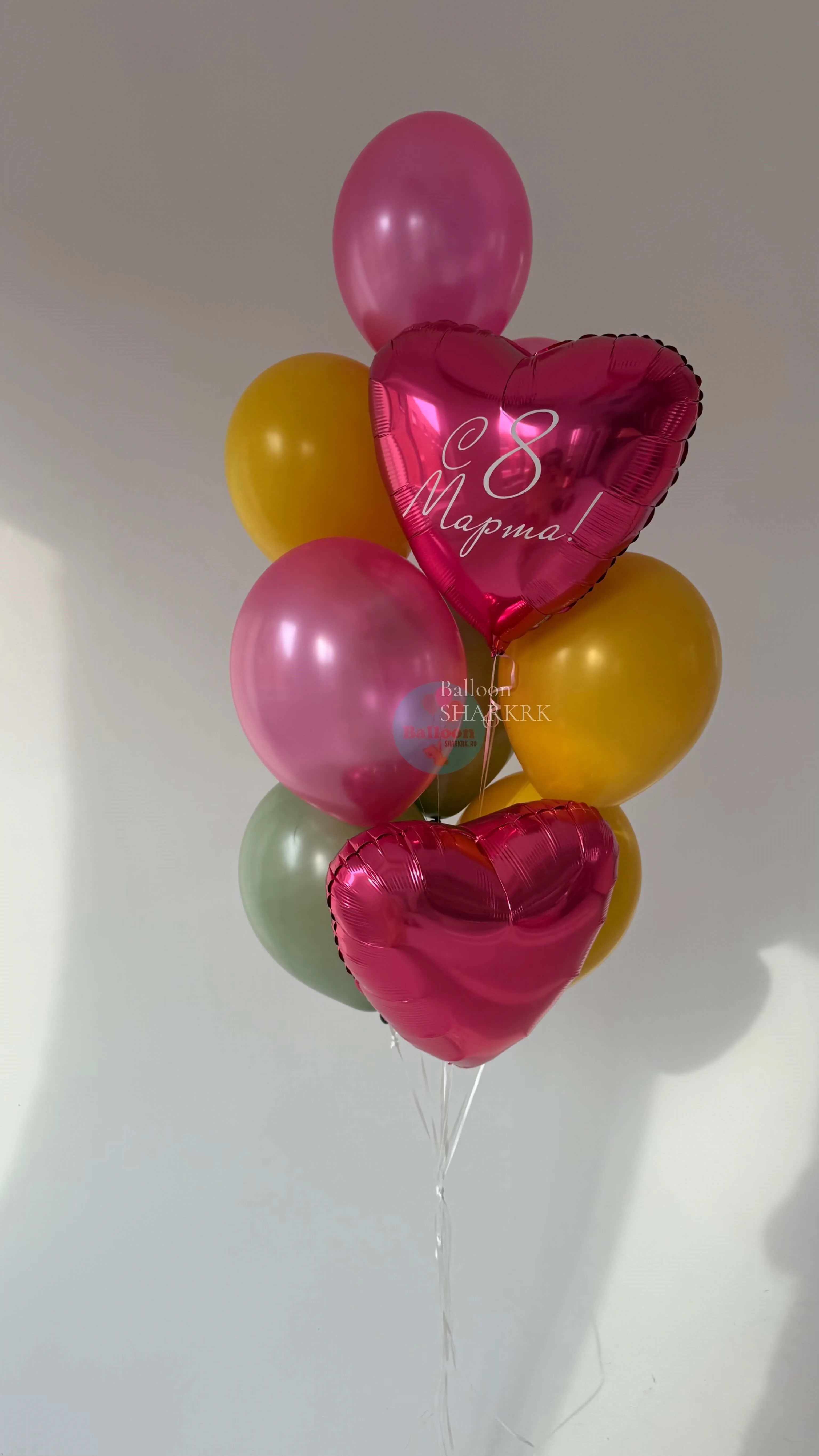 Праздничная композиция из шаров: фольгированные сердца с поздравлением, окружённые шарами пастельных тонов (розовый, жёлтый, зелёный), оформление для 8 Марта