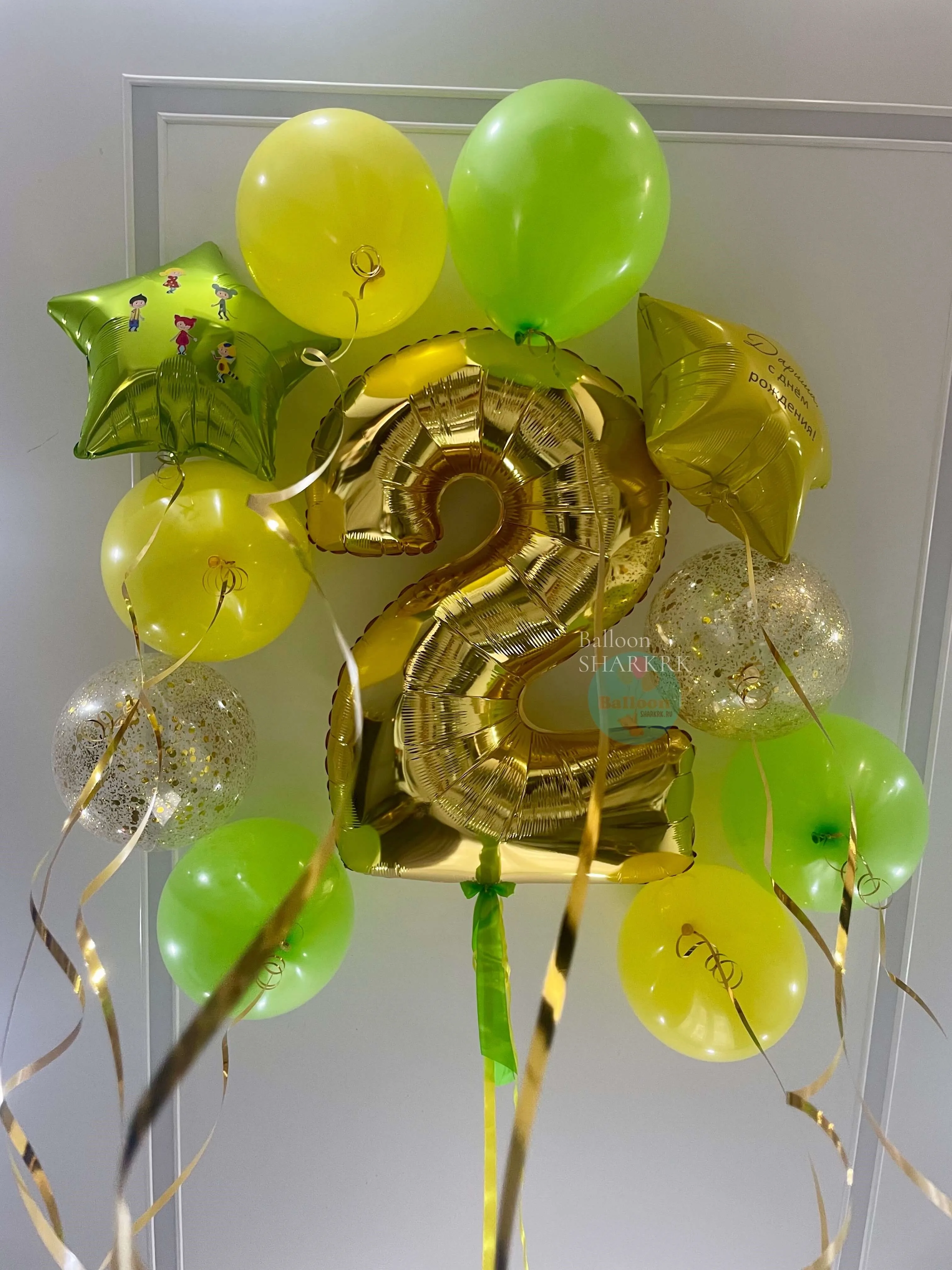 Золотая цифра «2» среди зелёных и блестящих шаров.